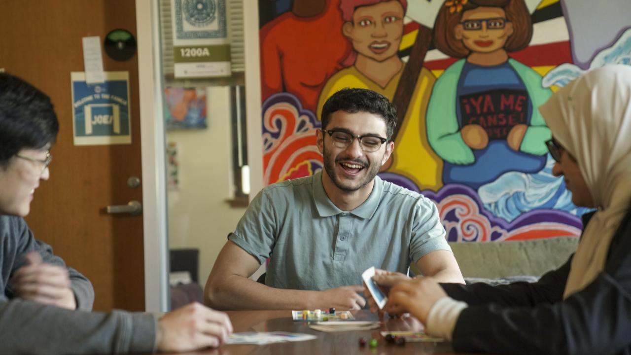 Three students laughing and hanging out while playing Lotería in one of the Cross Cultural Center’s many common areas.